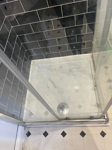 Shower enclosure with black tiles, a white tray and glass doors