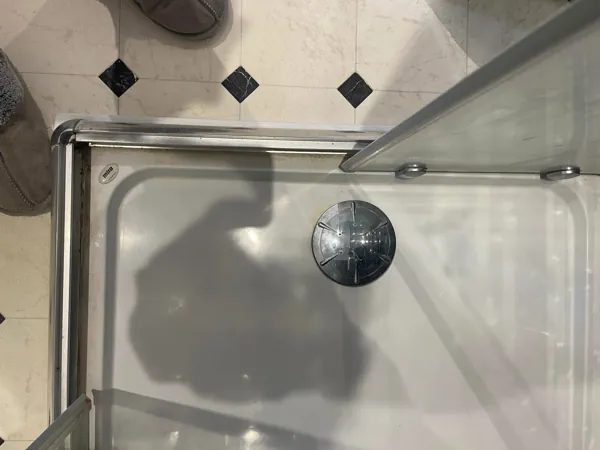Close-up of a shower tray, drain and door track