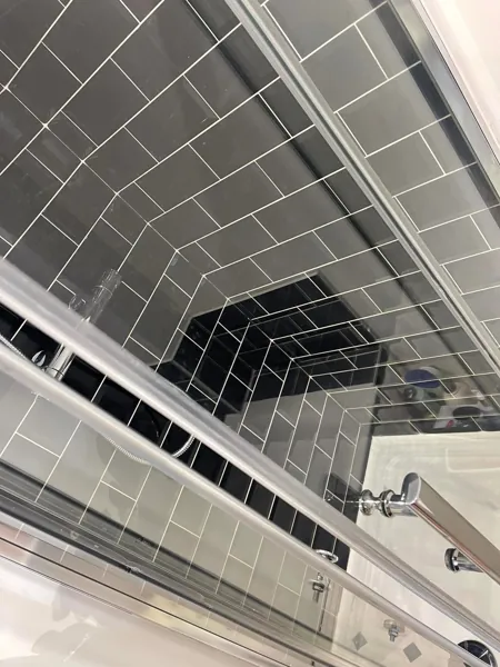 Glass shower screen and black tiled walls