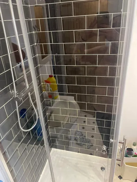 Shower enclosure with black tiled walls and a glass door